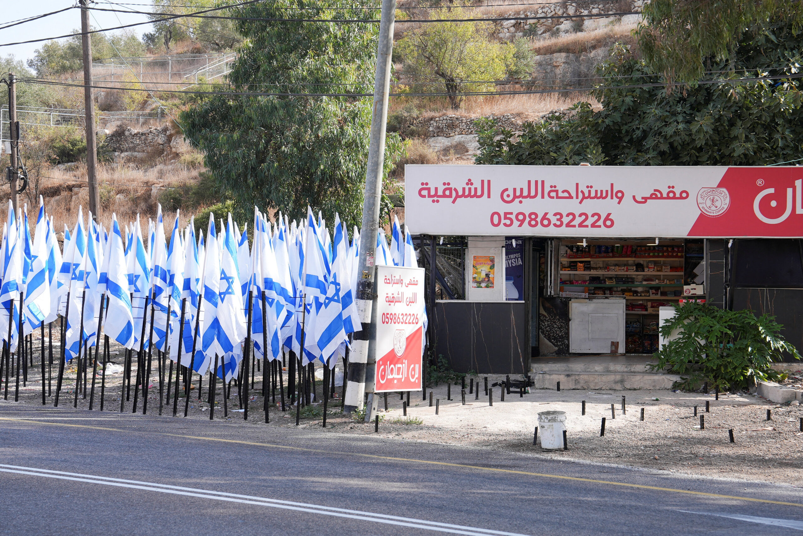 Israeli settlers flank Palestinian cafe with dozens of Israeli flags